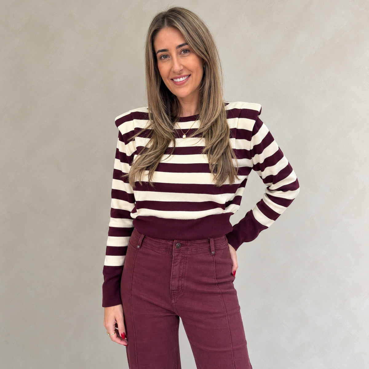Selene wearing the burgundy and cream striped padded shoulder jumper with burgundy trousers